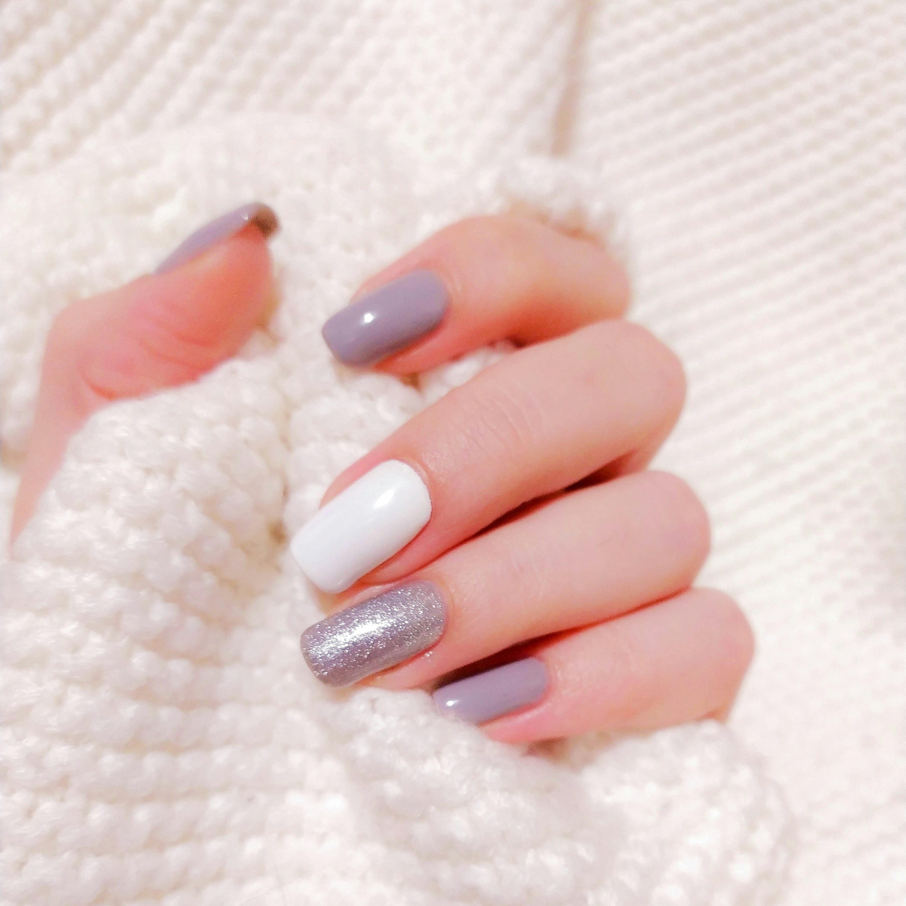 A hand resting on cream knitted fabric, nails painted in soft pastel pink